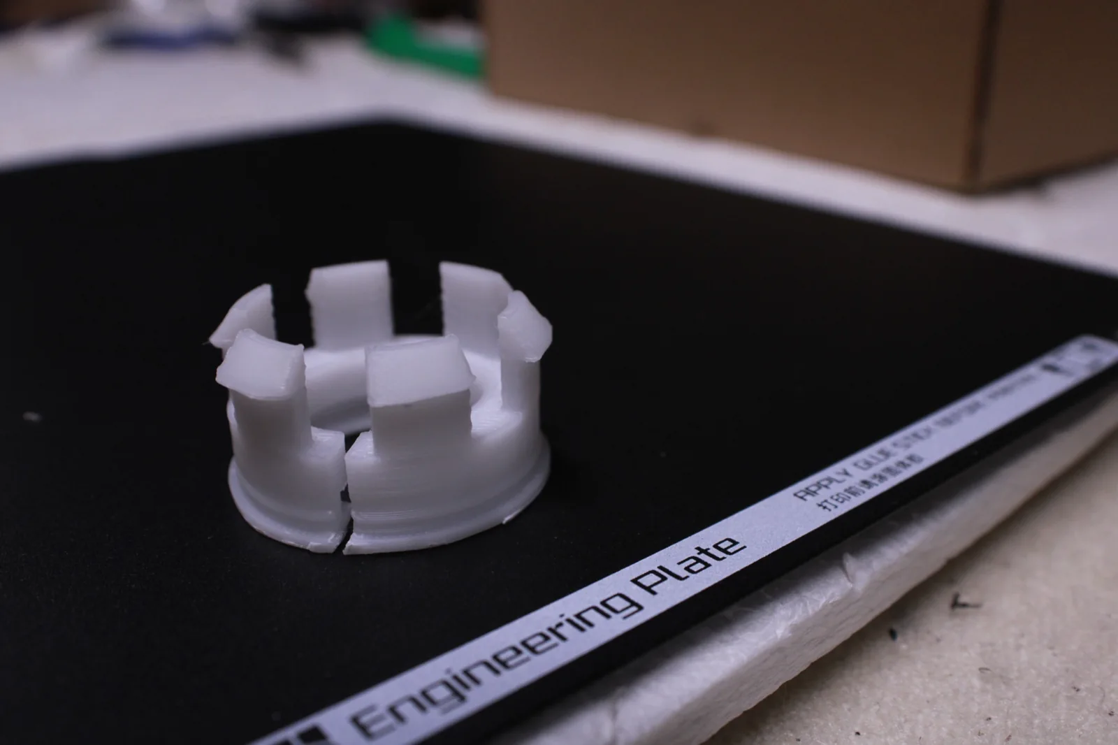 Petite pièce technique blanche imprimée en 3D sur une plaque de fabrication